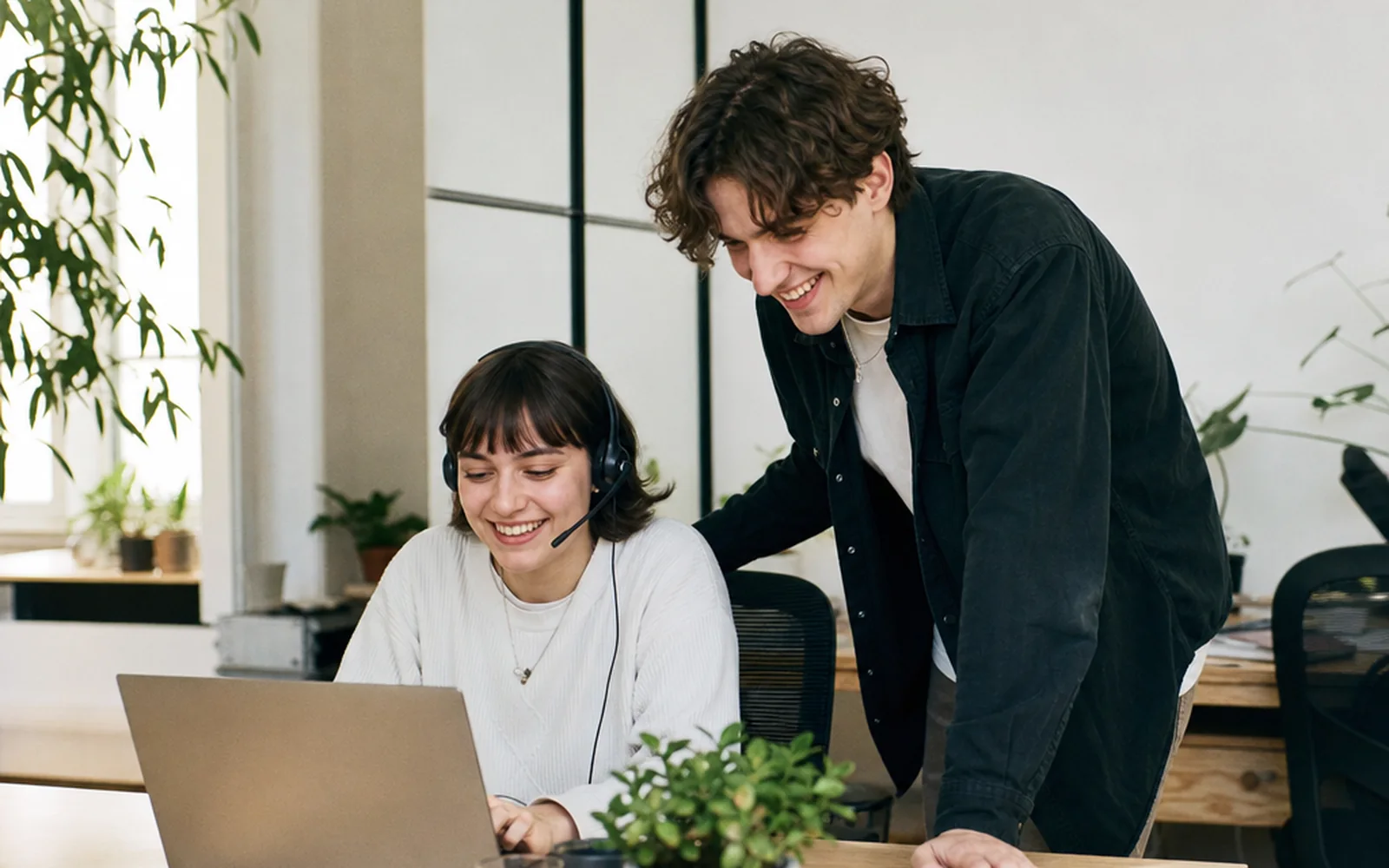 Zwei Mitarbeitende von Songbotschaft lachen gemeinsam über etwas auf einem Laptop